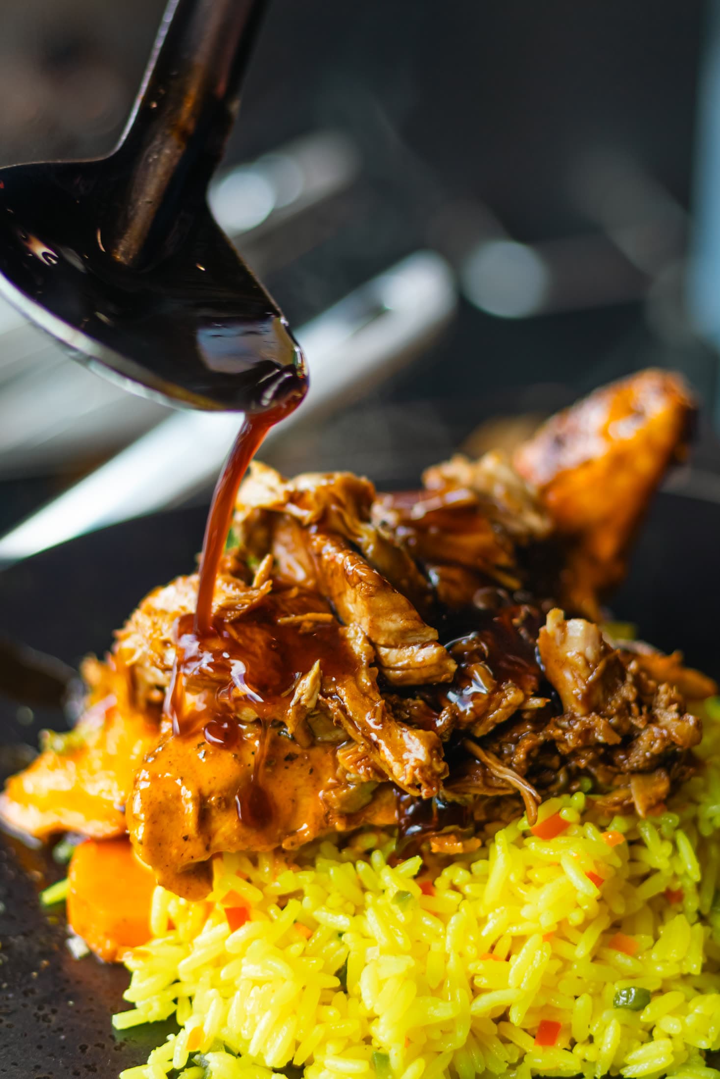 Sauce being poured over beef strips and yellow rice