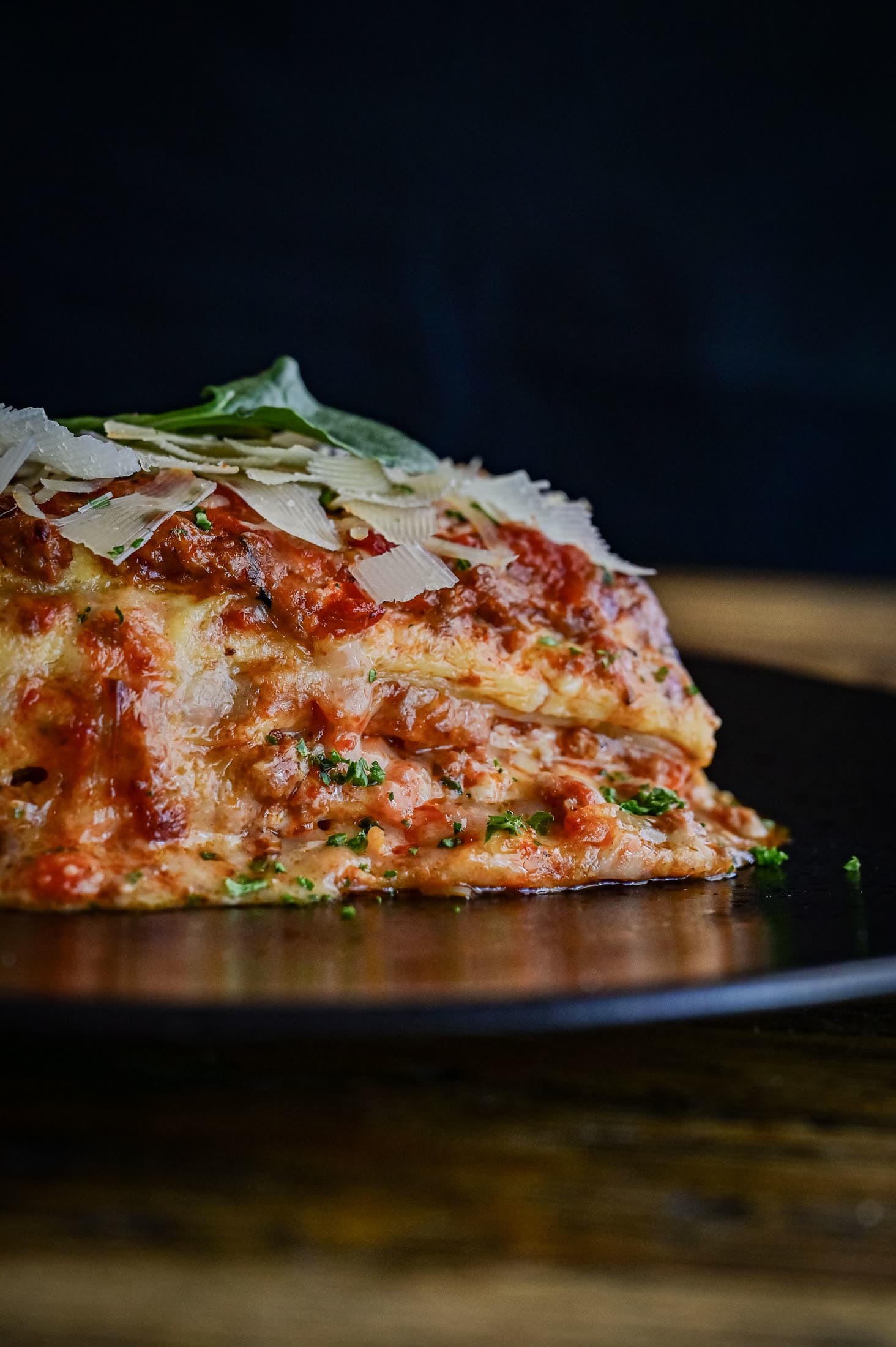 A close-up slice of lasagne with parmesan shavings