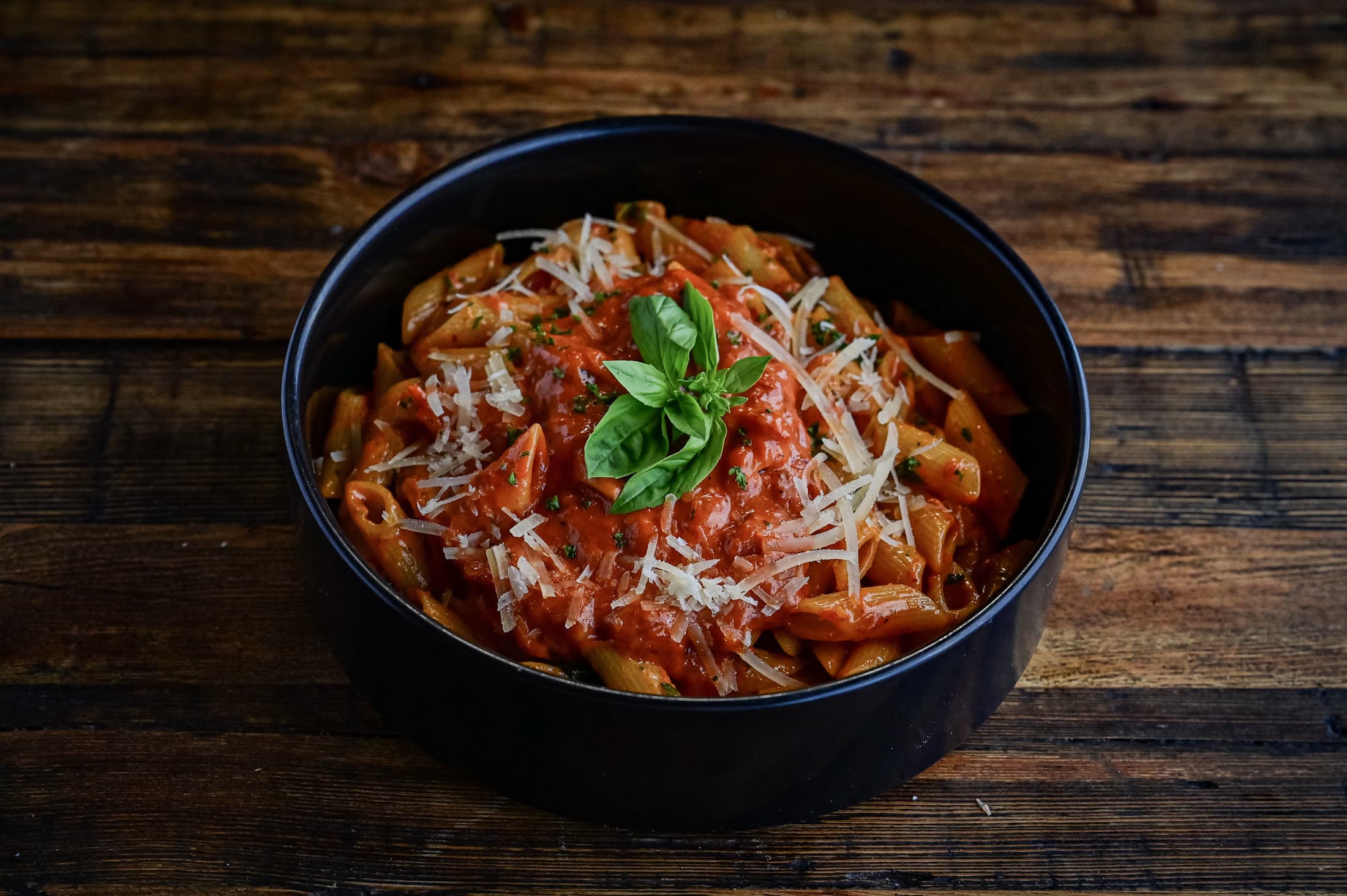 Penne pasta in rich tomato sauce topped with basil and parmesan