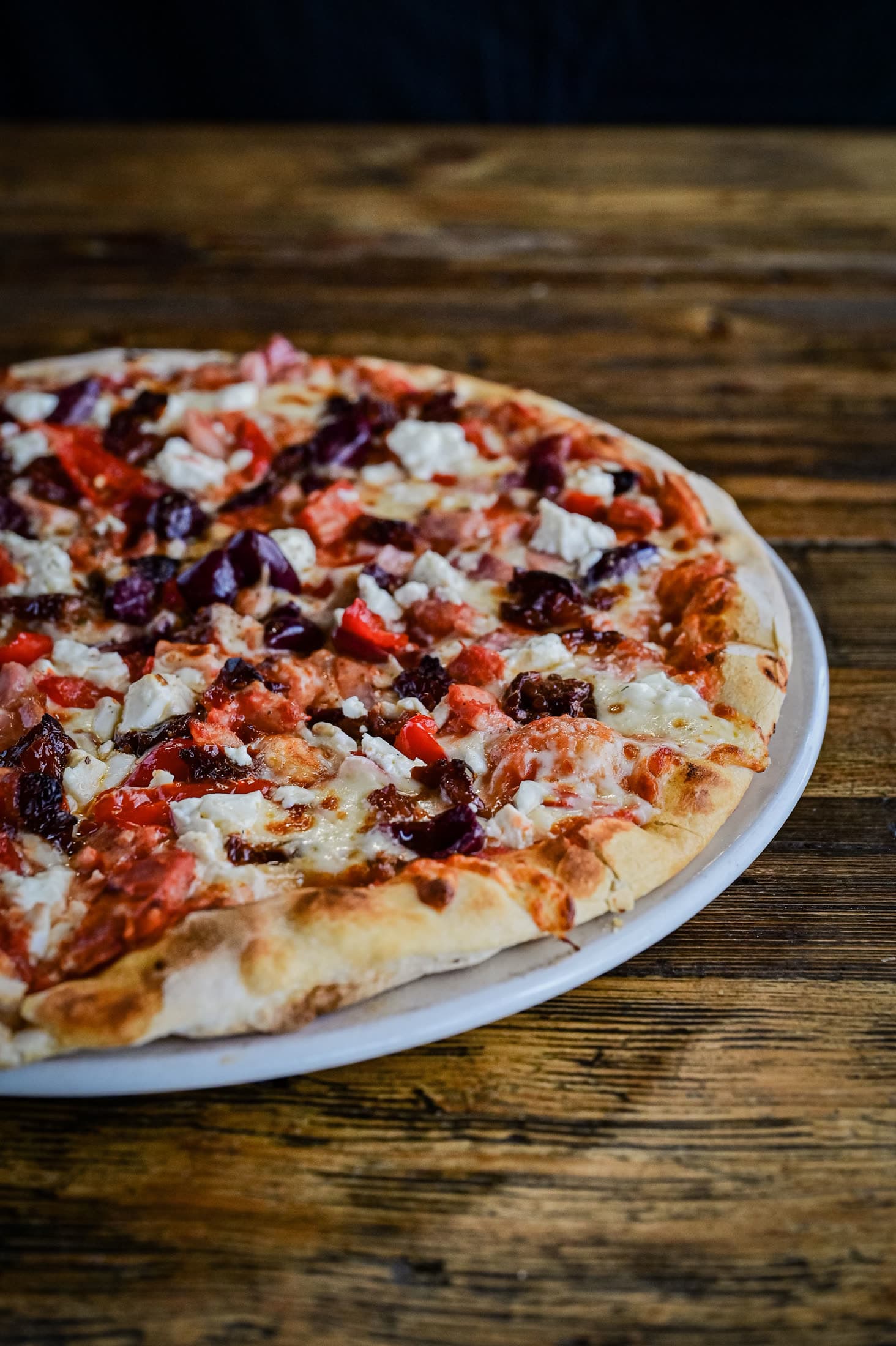 A freshly baked pizza with feta, peppers, and olives